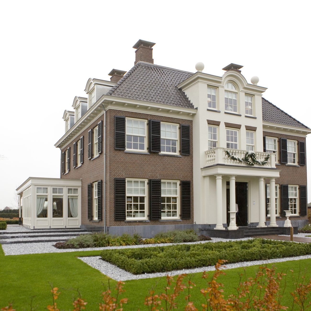 Neoclassicistische villa met symmetrische opbouw, balkon en klassieke details in groene landelijke setting